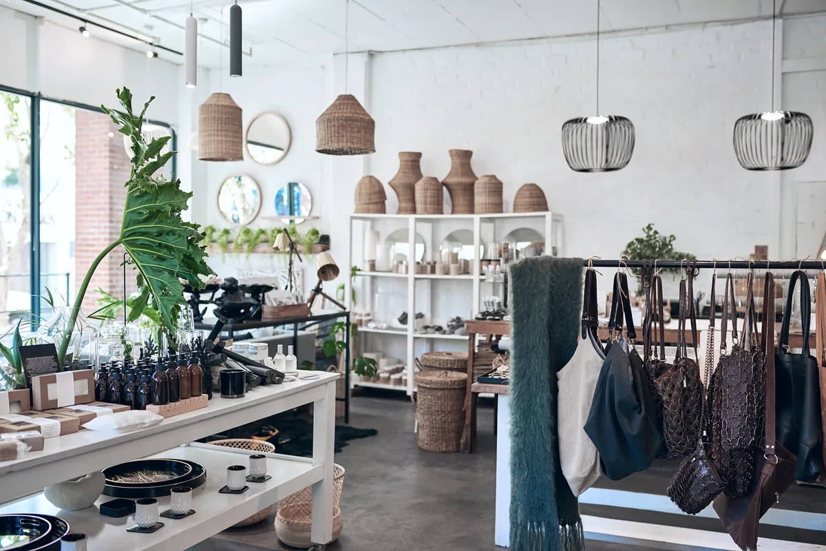White-brick gift shop with woven wicker vases, pendant lights, and a table of ceramics and home goods