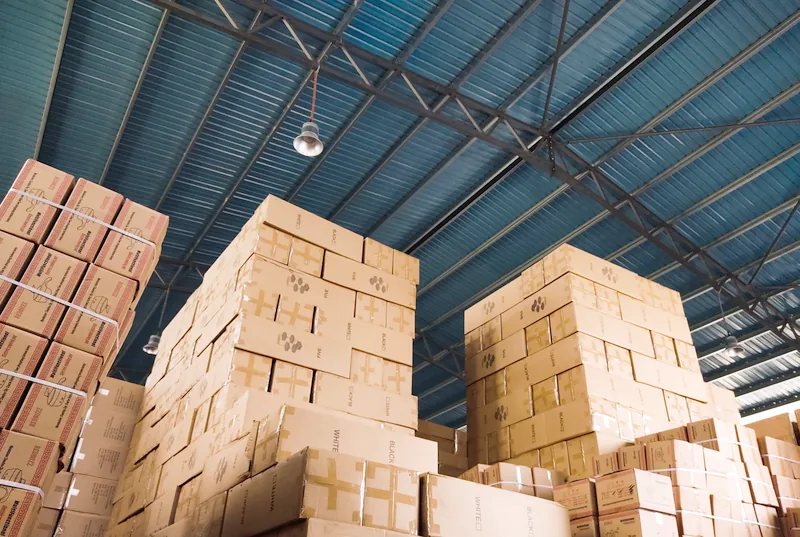 Stacked cardboard shipping boxes in a large distribution warehouse